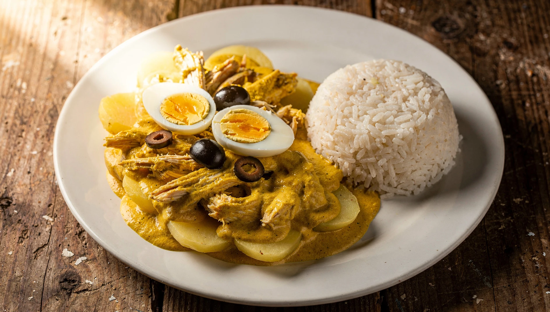 Plato de ají de gallina tradicional peruano con papas, huevo duro y aceitunas negras