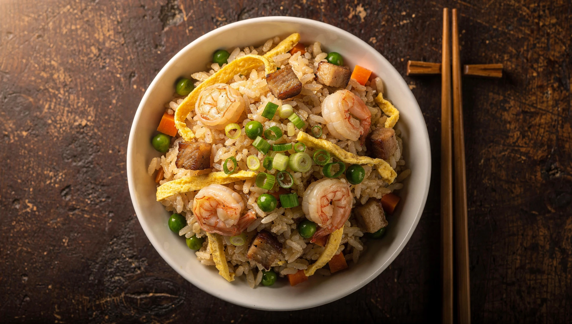 Arroz frito Yangzhou con camarones, cerdo asado, huevo en tiras, guisantes y zanahoria en un cuenco blanco