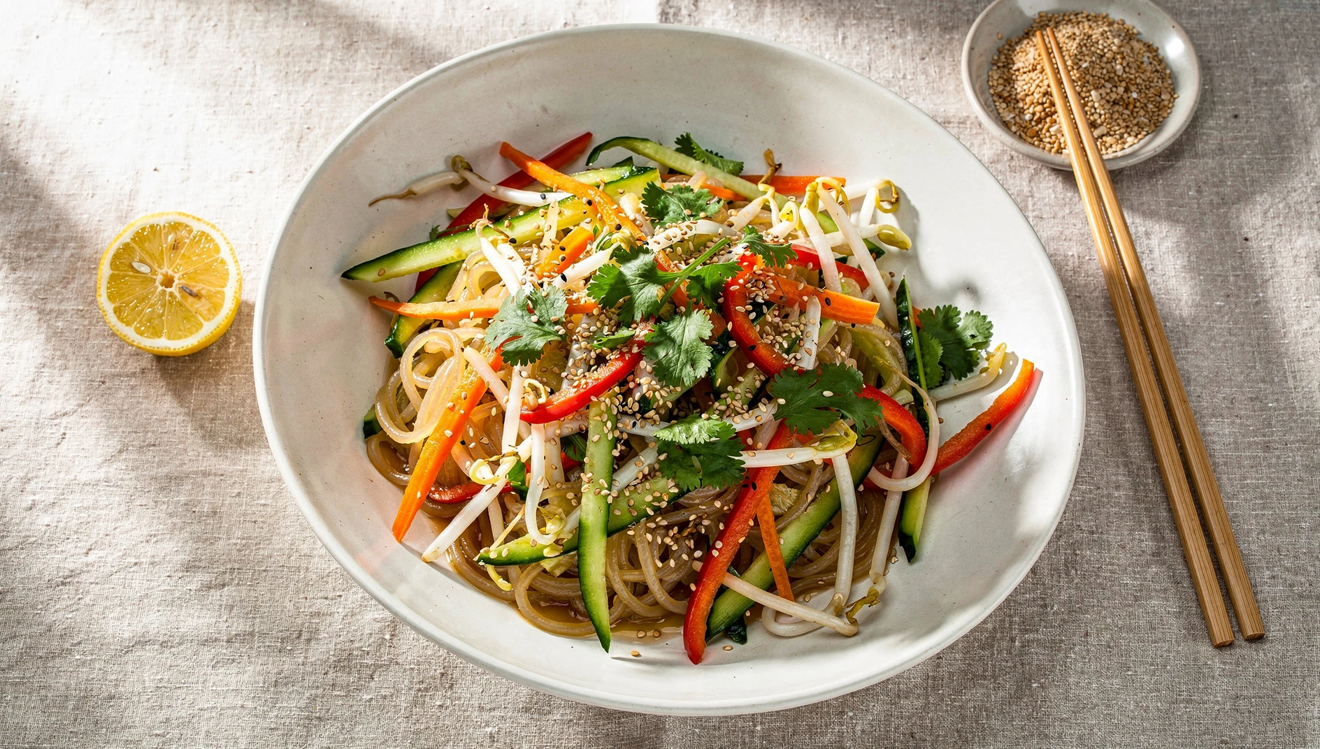 Ensalada de fideos fríos vegana con sésamo, limón, pepino, zanahoria y brotes de soja en un bol de cerámica