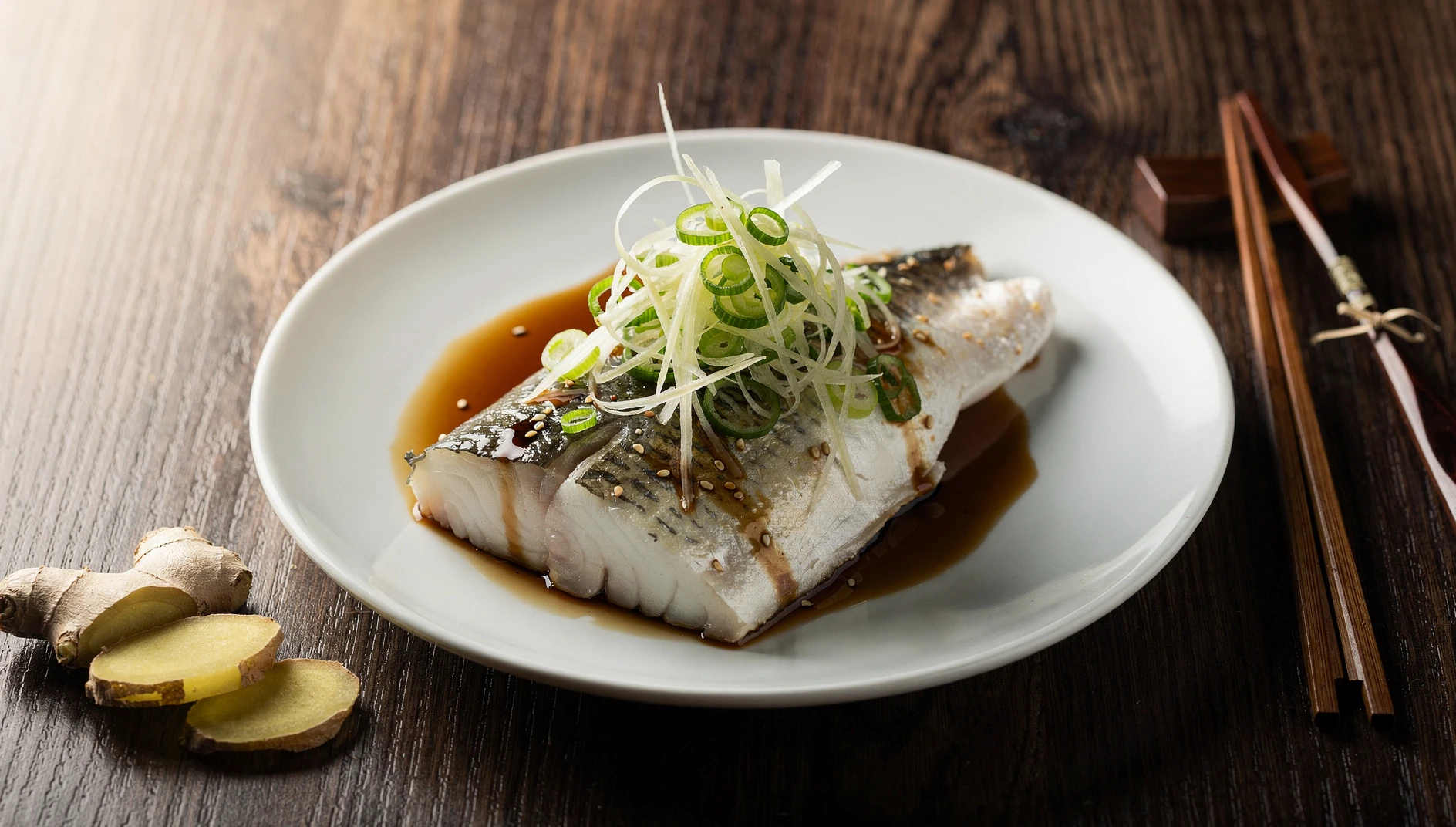 Filete de pescado blanco al vapor con juliana de kión fresco y cebollita china sobre plato de cerámica