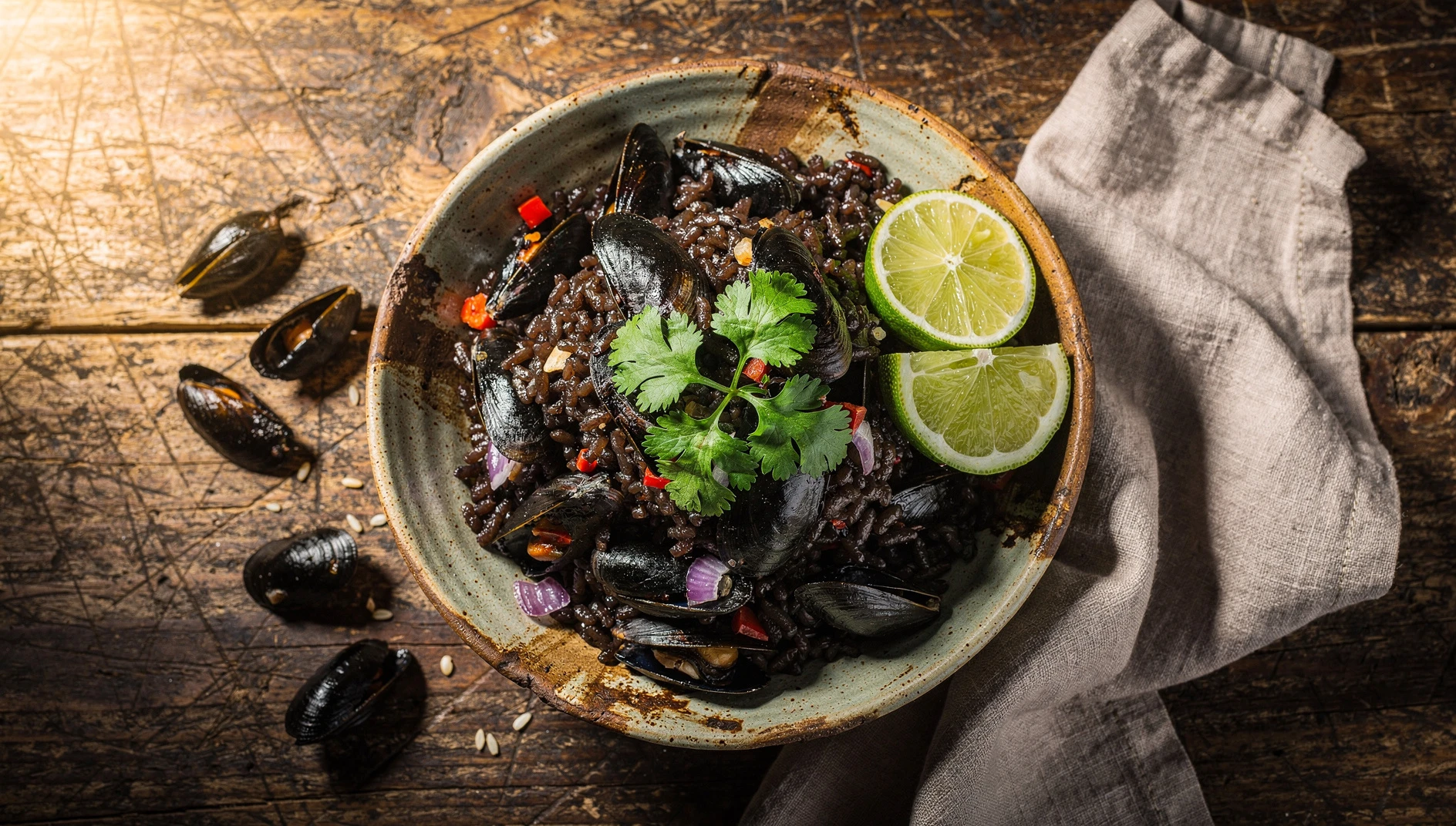 Arroz con conchas negras tumbesino servido en un bol de barro con cilantro fresco y rodajas de limón