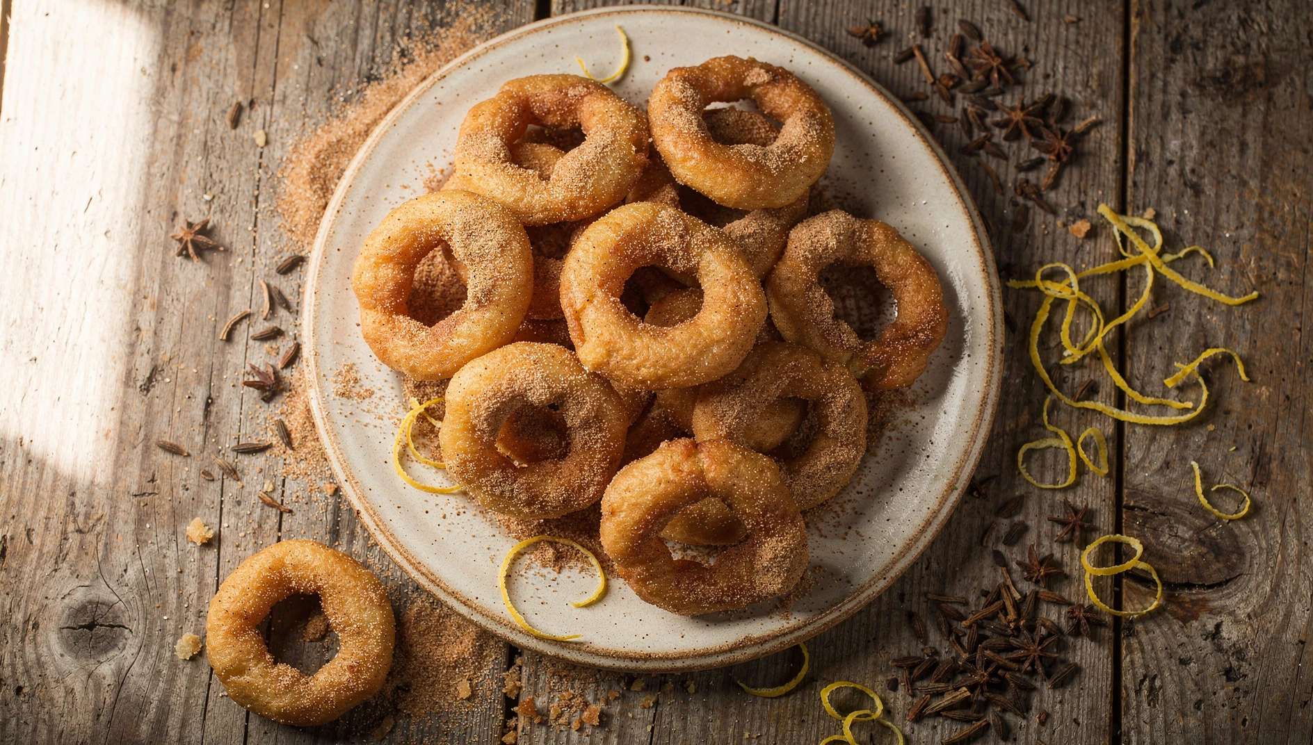 Bunyols de l'Empordà recién fritos espolvoreados con azúcar y canela sobre un plato de cerámica rústica