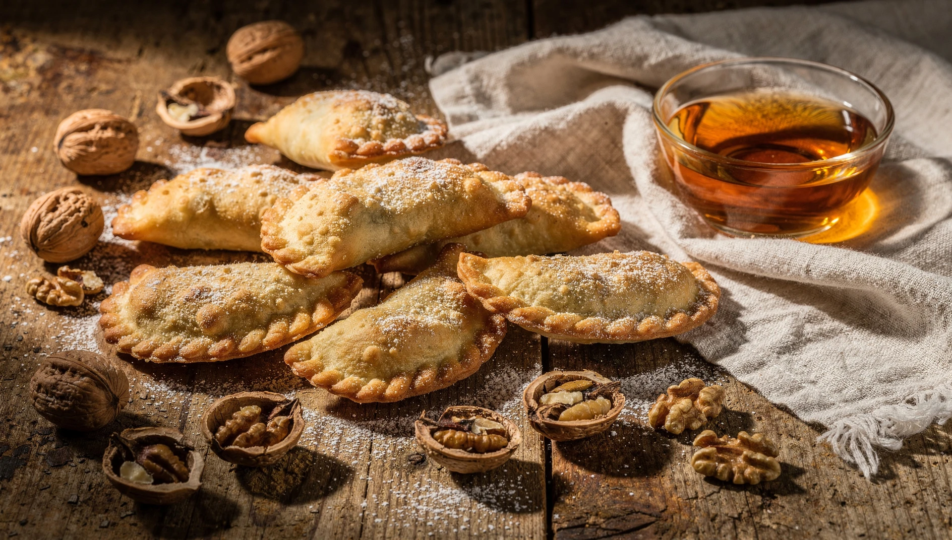 Casadielles asturianas recién fritas espolvoreadas con azúcar glas sobre una tabla de madera rústica