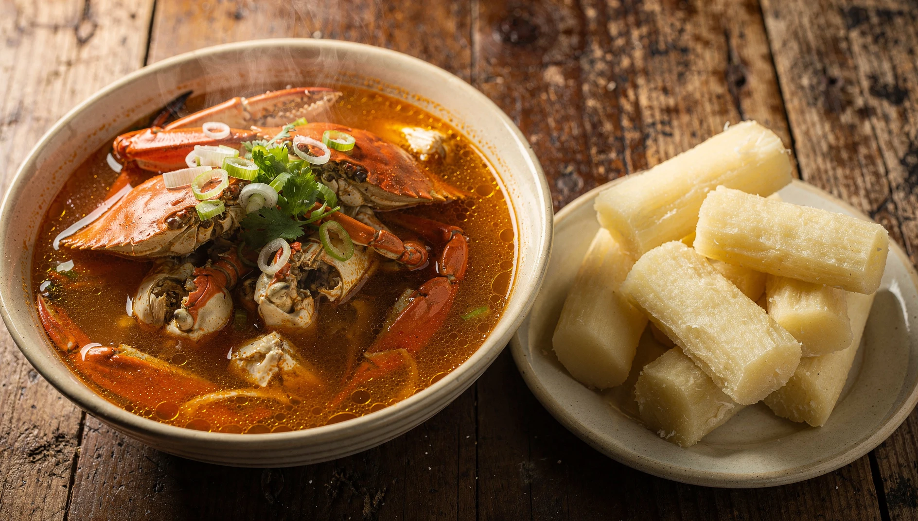 Tazón de chilcano de cangrejo tumbesino con caldo rojizo, trozos de cangrejo de manglar y culantro picado, acompañado de yuca sancochada