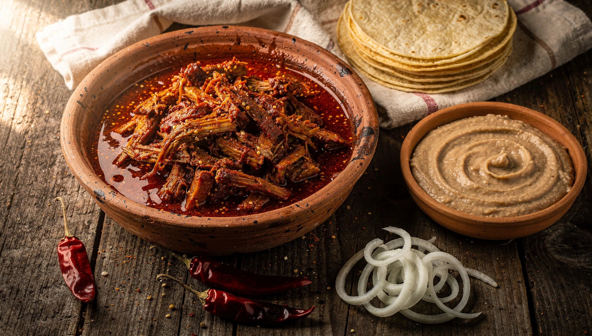 Chilorio sinaloense de cerdo deshebrado con salsa de chiles anchos servido en cazuela de barro con tortillas de maíz