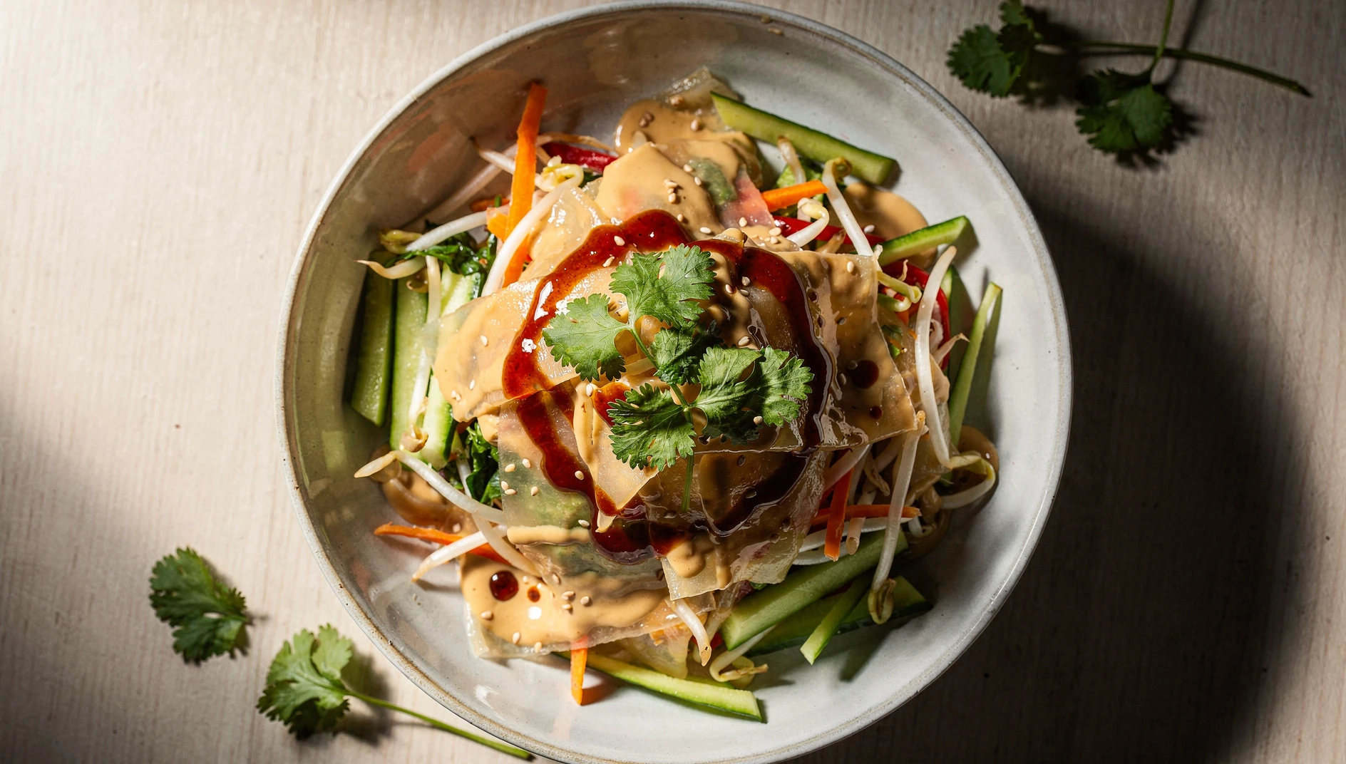 Ensalada dongbei da lapi con láminas de almidón de frijol mungo, vegetales en juliana y salsa de sésamo en un bol de cerámica