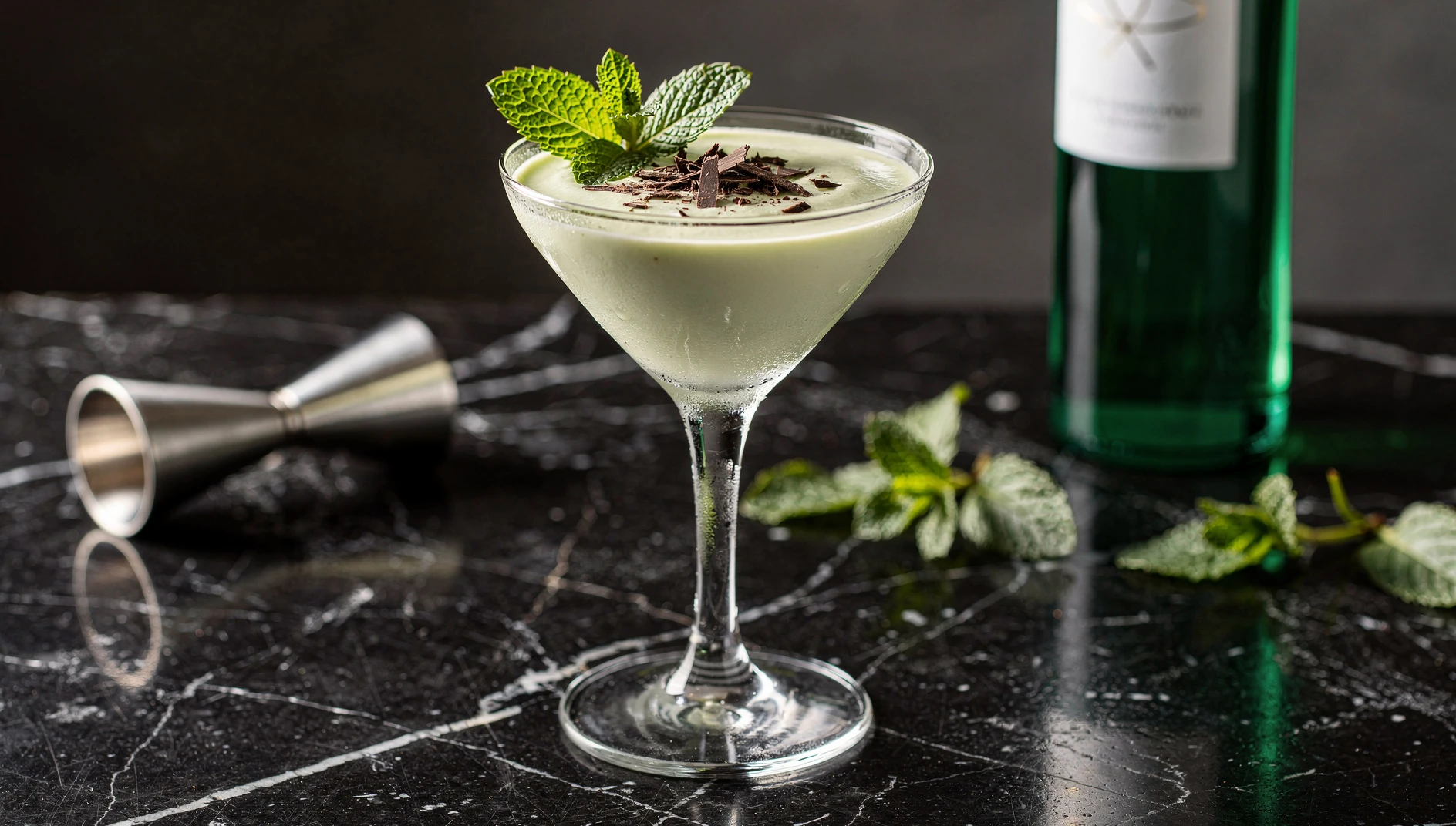Copa de cóctel Grasshopper cremoso de color verde pálido con menta fresca y virutas de chocolate