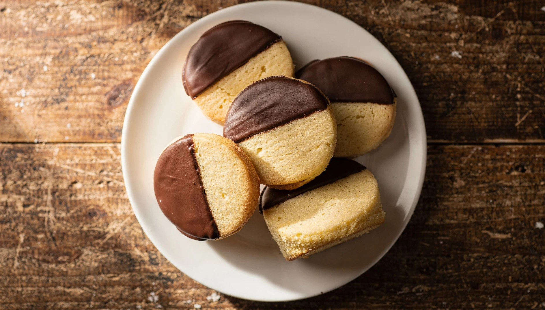 Halfmoon cookies de Utica con glaseado bicolor de chocolate y vainilla sobre plato blanco