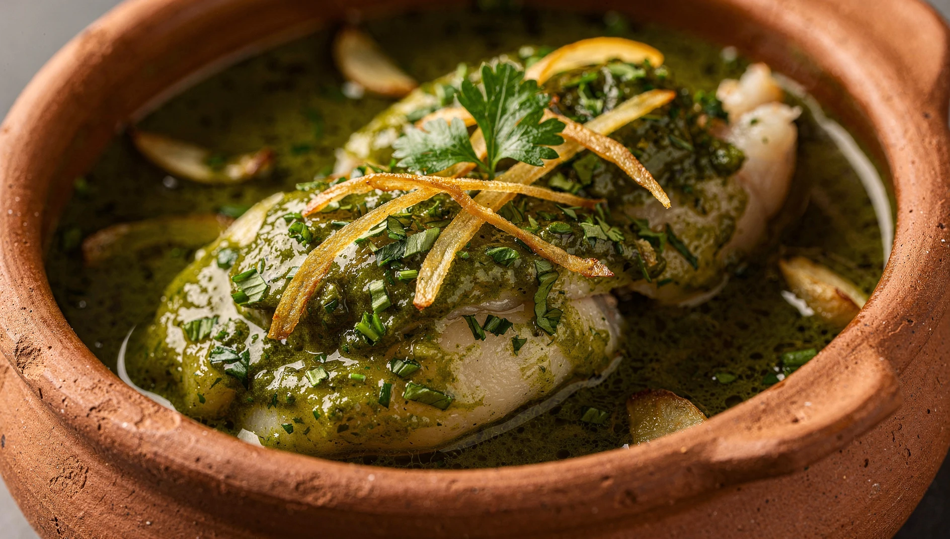 Kokotxas de merluza en salsa verde servidas en cazuela de barro con ajo y perejil fresco