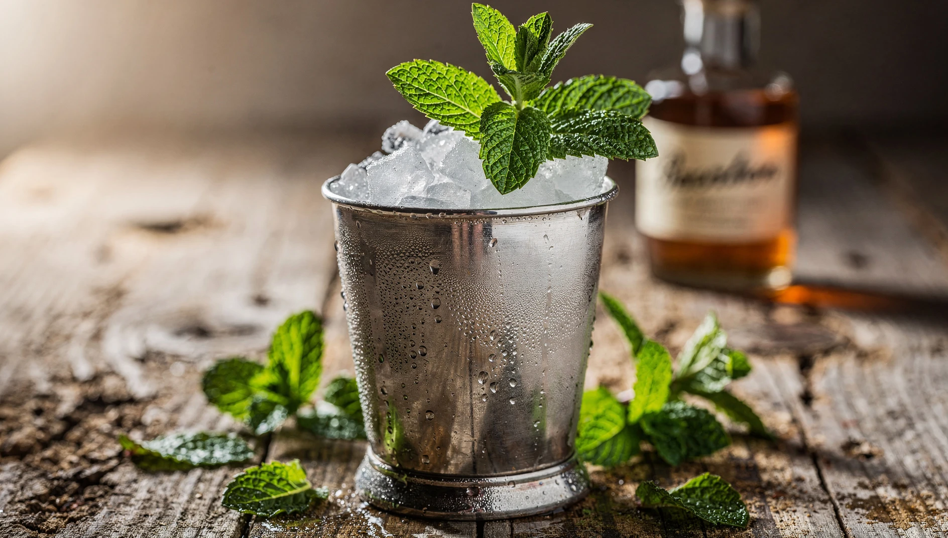 Mint Julep servido en vaso de plata con hielo picado y ramita de menta fresca