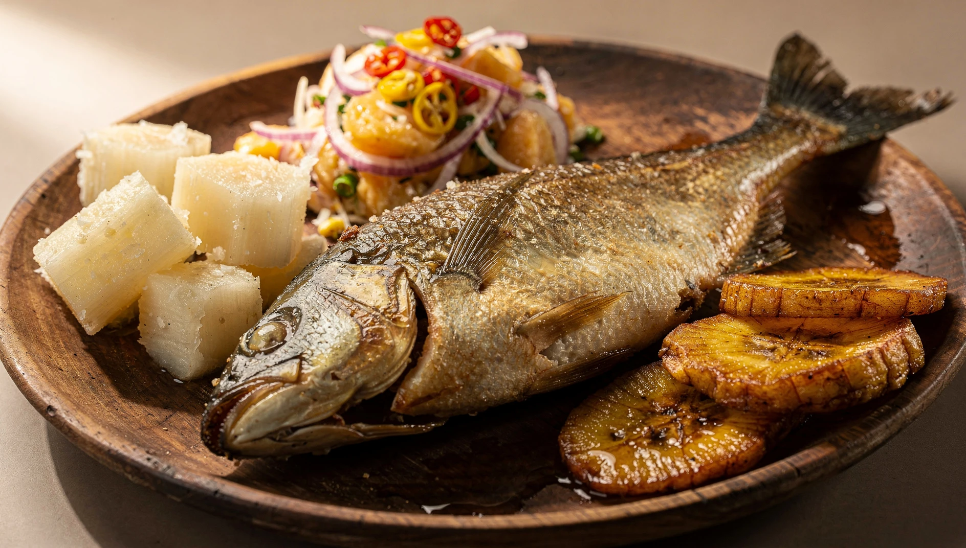 Palometa frita amazónica entera con piel dorada y crujiente, servida con yuca y plátano maduro frito