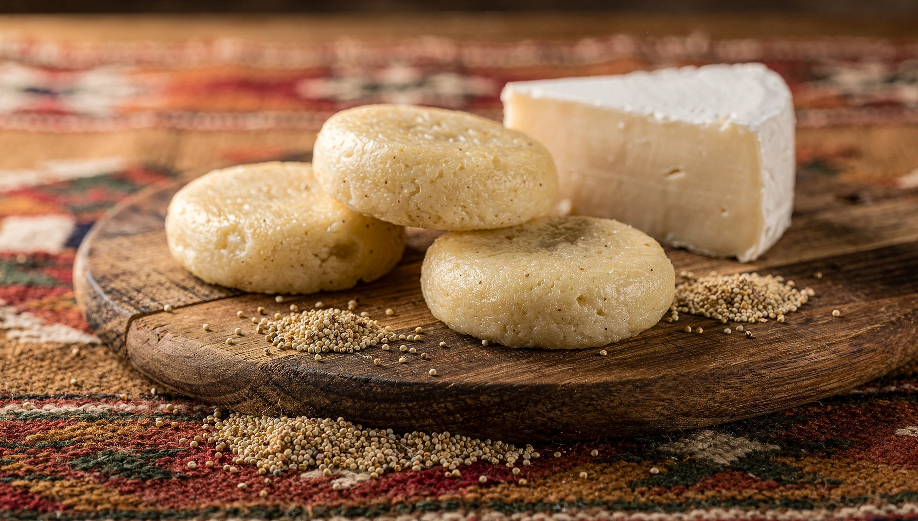 Quispiños puneños cocidos al vapor sobre tabla de madera rústica con queso fresco y granos de quinua