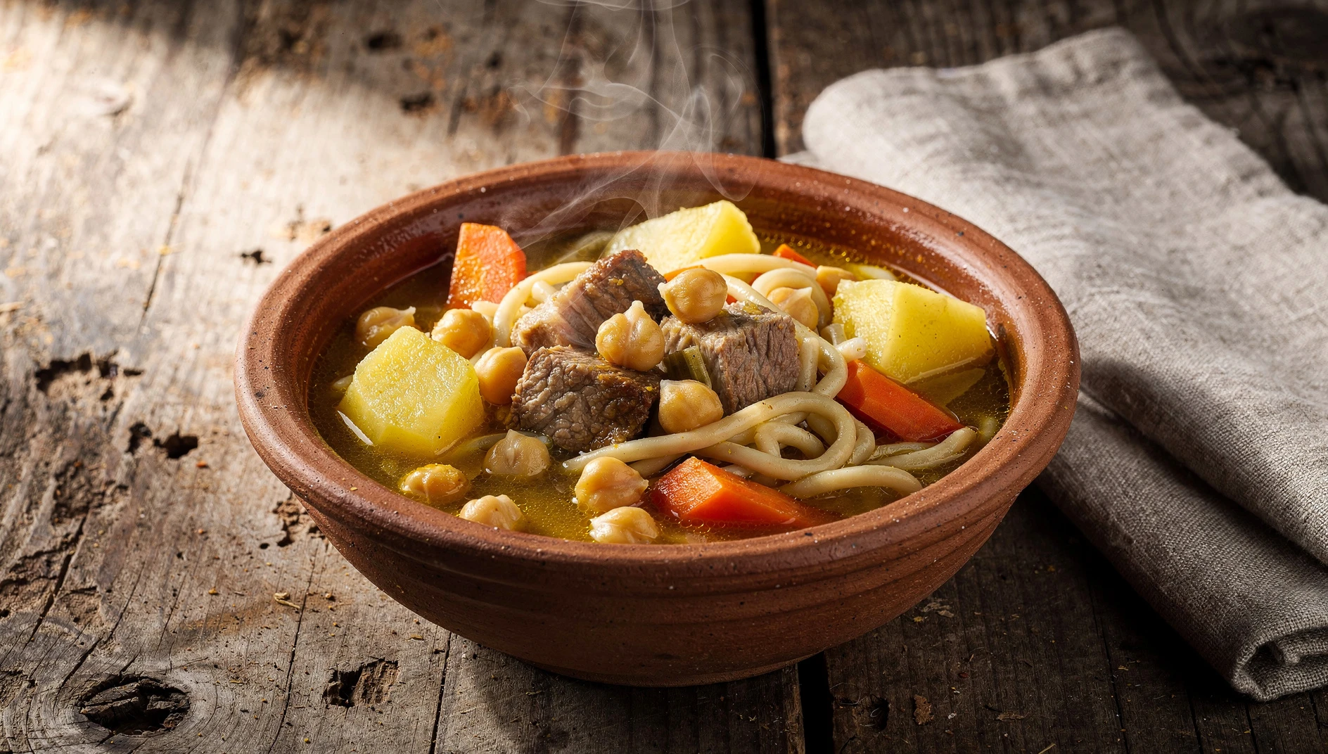 Plato de rancho canario tradicional con garbanzos, papas, fideos y carne en un caldo dorado