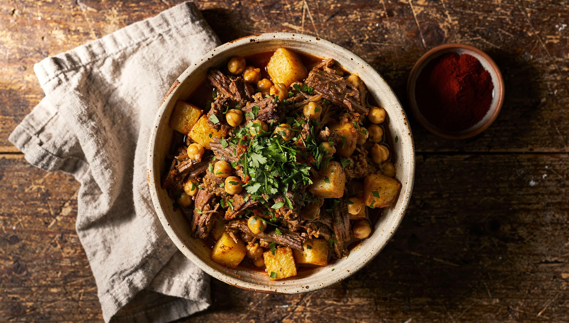 Ropa vieja canaria servida en cazuela de barro con garbanzos, carne deshilachada y patatas fritas
