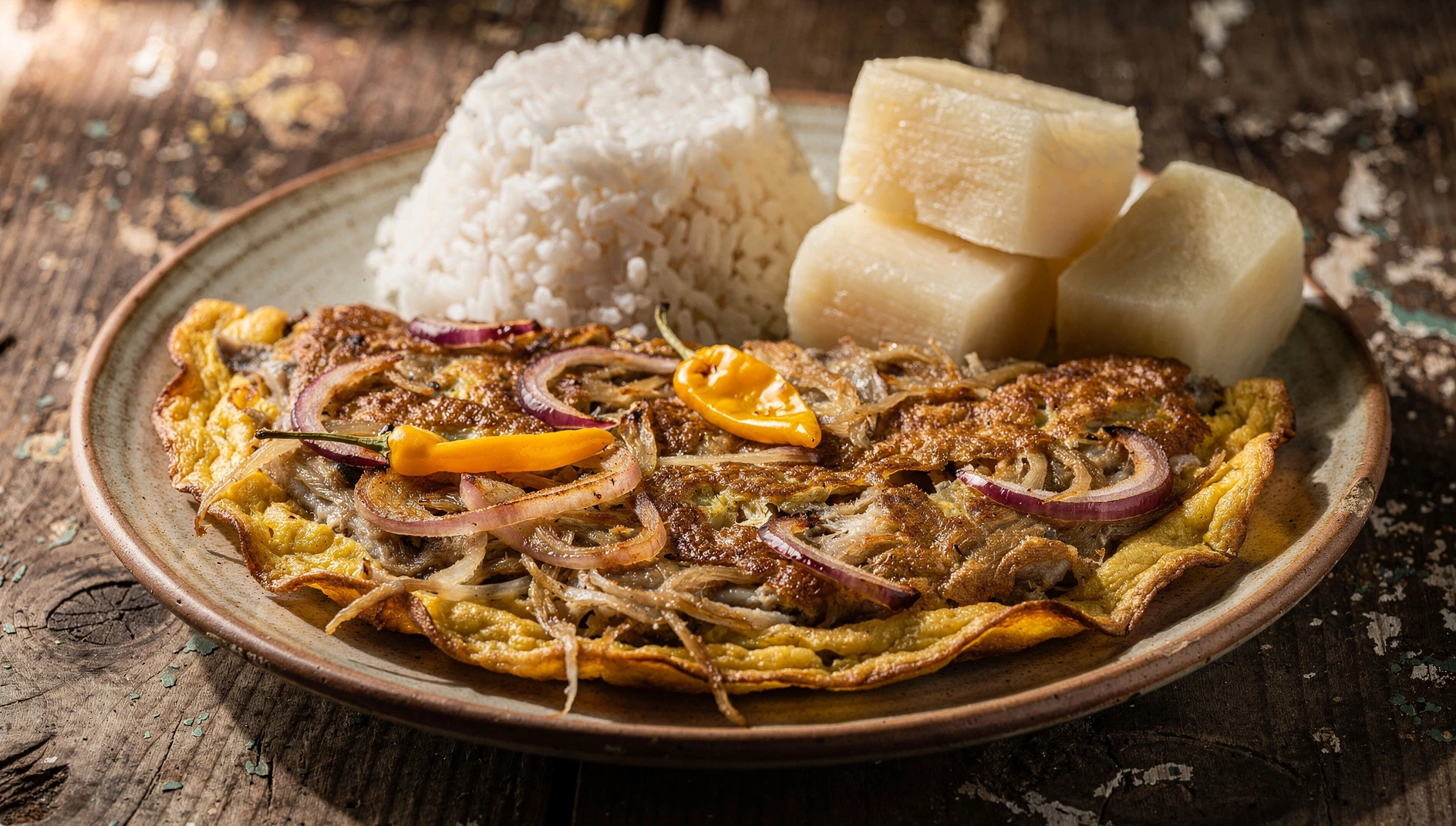 Tortilla de raya norteña dorada en plato rústico con yuca sancochada y arroz blanco al fondo