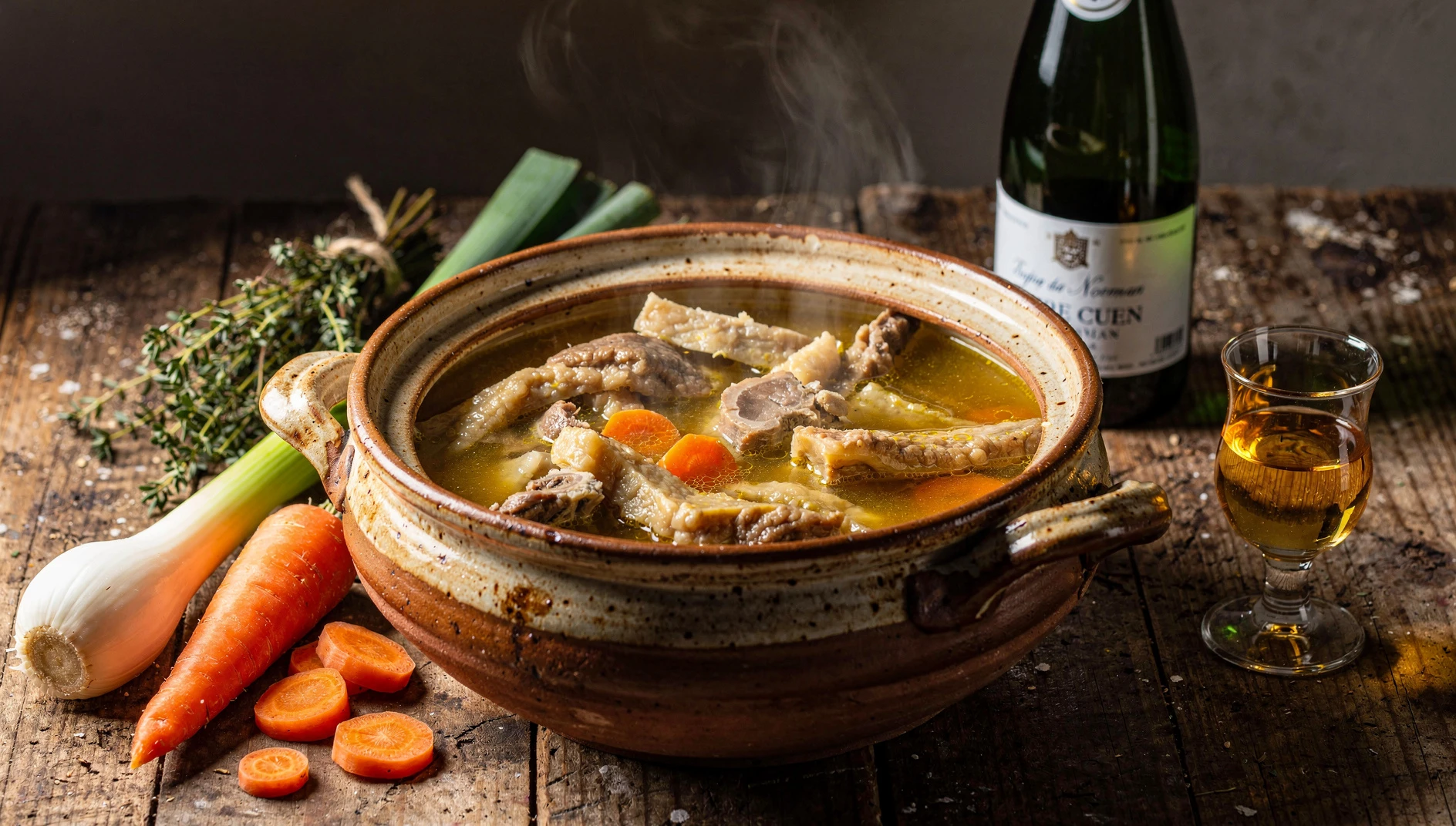 Bol de tripes à la mode de Caen con verduras y sidra normanda sobre mesa de madera