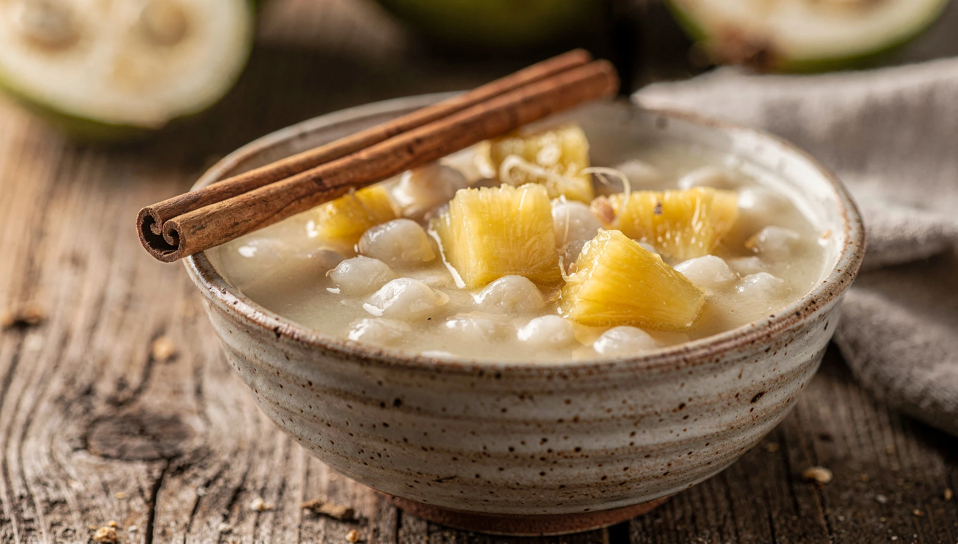 Tazón de champús de guanábana limeño con mote, piña y canela sobre mesa de madera
