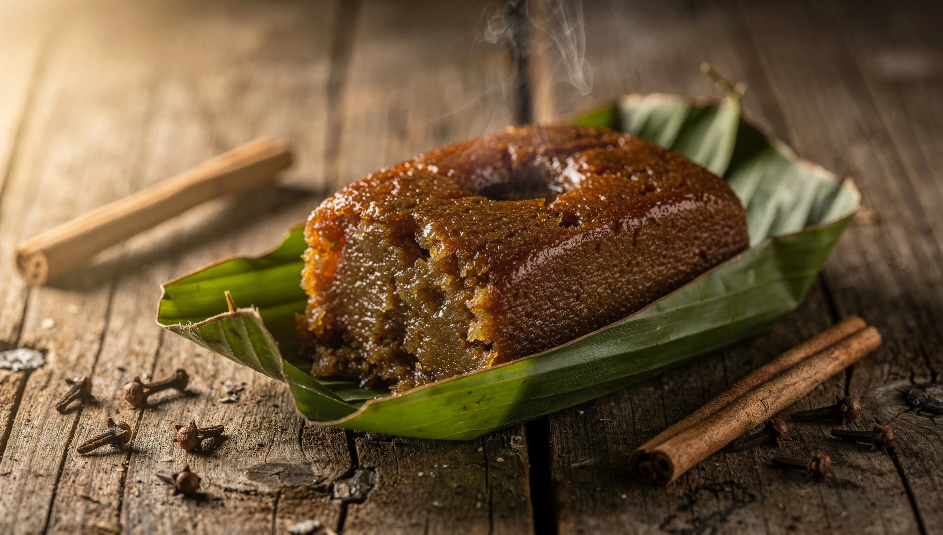 Chapana de yuca costeña envuelta en hoja de plátano sobre mesa de madera con canela y clavo de olor