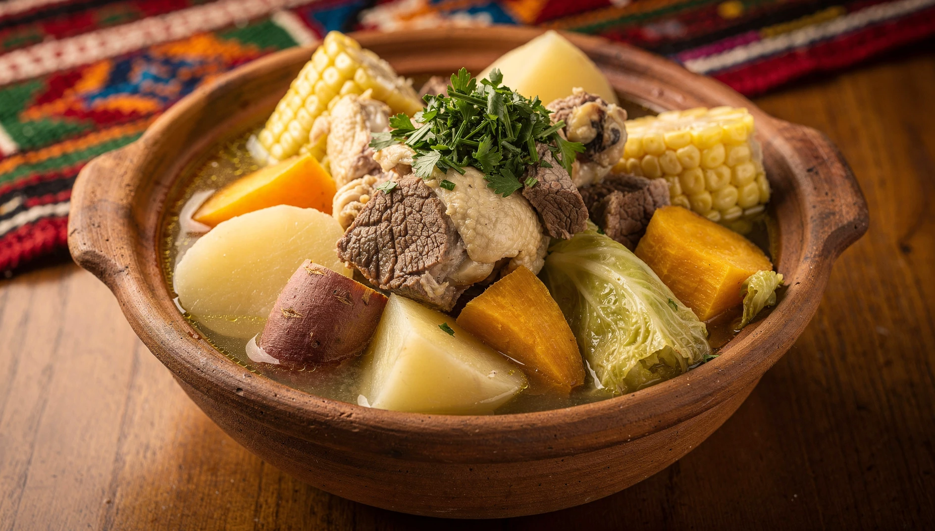 Sancochado oroyino servido en olla de barro con carnes, papas, camote, yuca, choclo y repollo en caldo dorado